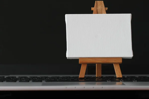 Tela bianca e cavalletto in legno sul computer portatile come concetto — Foto Stock