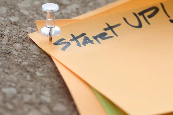 Close up on pin and start up word on sticky note with cork board — Stock Photo, Image