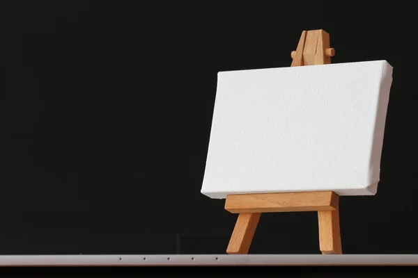 Пустой холст и деревянный мольберт на ноутбуке как концепция — стоковое фото