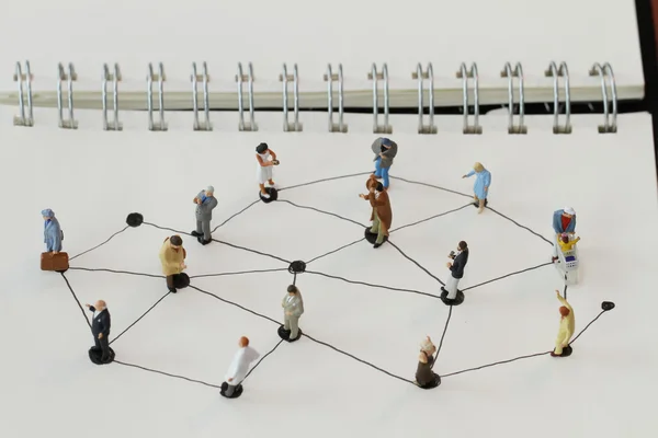 Close up of miniature people with social network diagram on open — Stock Photo, Image