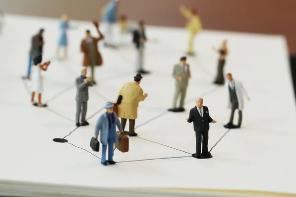 Close up of miniature people with social network diagram on open — Stock Photo, Image