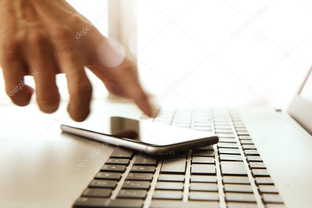 Businessman hand using laptop and mobile phone in office