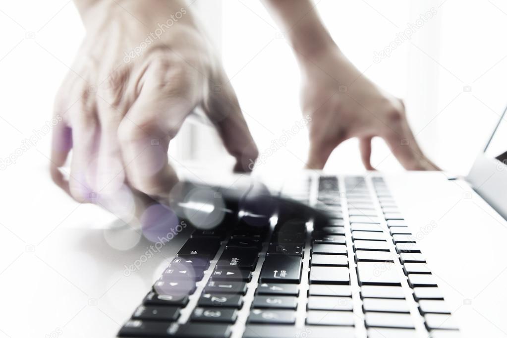 Businessman hand using laptop and mobile phone  on wooden desk a