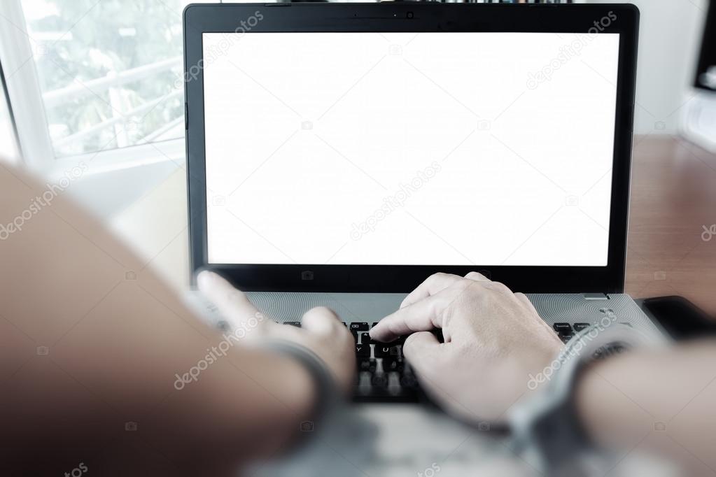Businessman hand in handcuffs at wooden desk with laptop compute