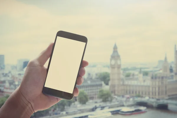 Man hand holding blank screen smartphone against london city blu — 图库照片