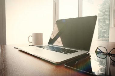 Bilgisayarı ve ahşap masasında akıllı telefonu olan bir ofis. 