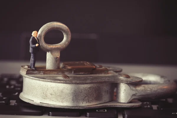 Internet security concept-miniature businessman stand on old key — Stock Photo, Image