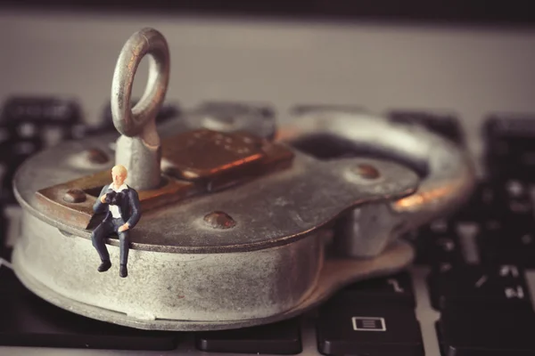 Internet security concept-miniature businessman stand on old key — Stock Photo, Image