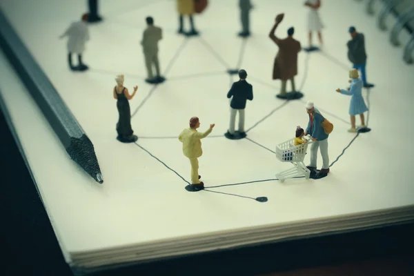 Close up of miniature people with social network diagram on open — Stock Photo, Image