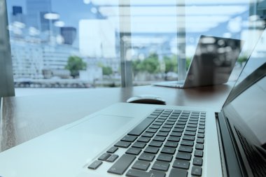 Bilgisayarı ve ahşap masasında akıllı telefonu olan bir ofis. 