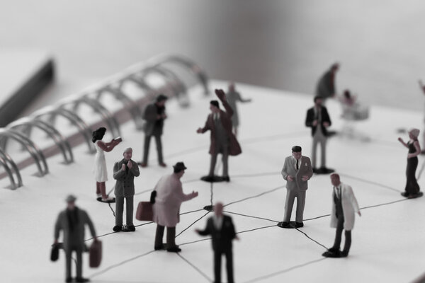 close up of miniature people with social network diagram on open