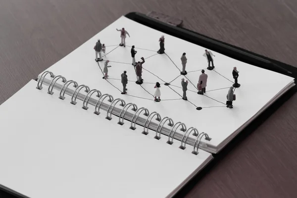 Close up of miniature people with social network diagram on open — Stock Photo, Image