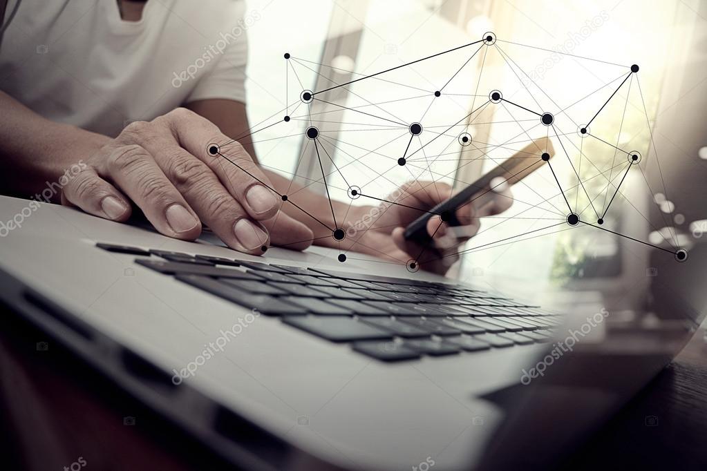 designer hand working and smart phone and laptop on wooden desk 