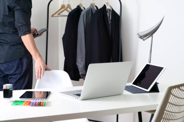  Dizüstü bilgisayarı, tableti, kırtasiyesi ve askıda asılı iş gömlekleri olan modern bir ofis. Uzaktan çalışma, profesyonel yaşam tarzı, üretkenlik, yaratıcı stüdyo ve iş hazırlığı temaları için uygun.