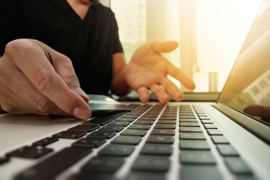 close up of hands using laptop and holding credit card as Online