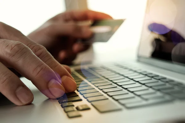 Mãos usando laptop e segurando cartão de crédito com mídia social dia — Fotografia de Stock