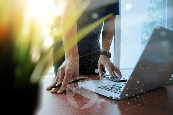 Designer hand working laptop with green plant foreground on wood — Stock Photo, Image