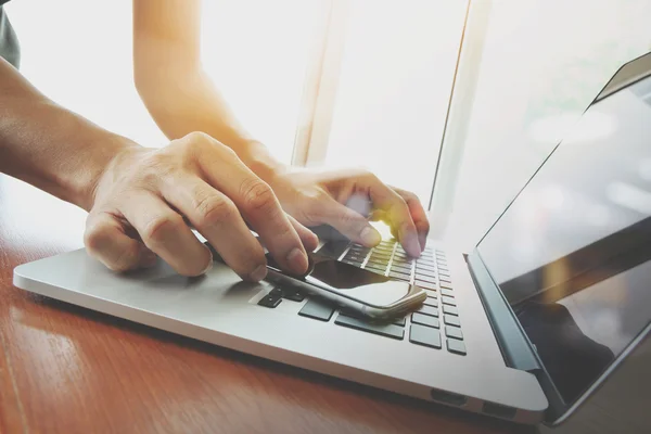 Designer hand working and smart phone and laptop on wooden desk — Stock Photo, Image