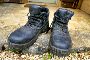 A pair of black steel toe capped heavy duty work boots coated in sawdust after logging clipart
