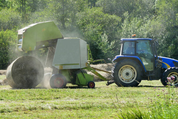 Baler opening to release a large round compacted hay bale