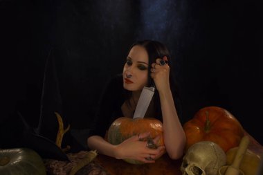 Güzel gotik kız, arka planda bıçak ve balkabağıyla poz veriyor.