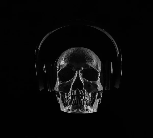 Skull with headphones in red light over dark background