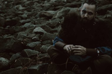 Acımasız İskandinav savaşçısı kayalarda oturuyor.