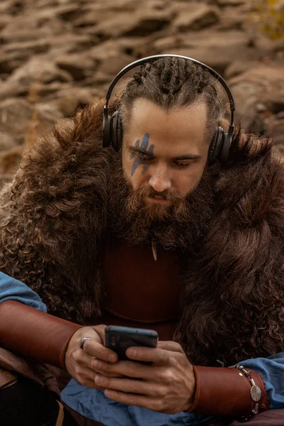 Brutal Scandinavian Warrior Sitting Rocky Sea Shore Smart Phone Headphones — Stock Photo, Image