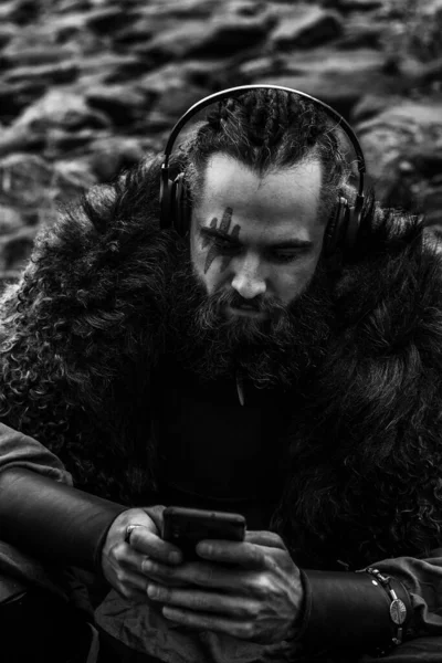 Brutal Scandinavian Warrior Sitting Rocky Sea Shore Smart Phone Headphones — Stock Photo, Image