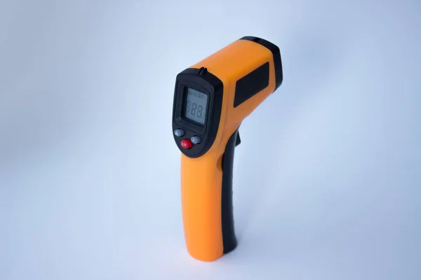 Infrared thermometer (thermometer gun) for measuring temperature over white background. Covid-19 spread prevention concept.