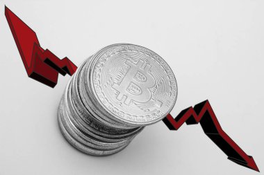 Beyaz zemin üzerinde kırmızı ok olan bitcoin yığını. Bitcoin konseptinin düşüşü.