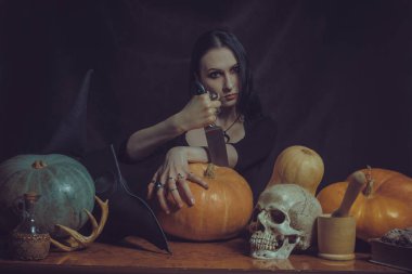 Güzel gotik kız balkabağı ve bıçakla poz veriyor.