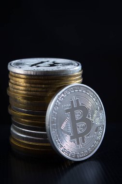 Bir gümüş bitcoin ve arka planda bir yığın bitcoin