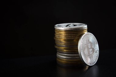 Bir gümüş bitcoin ve siyah arkaplan üzerinde bitcoin yığını