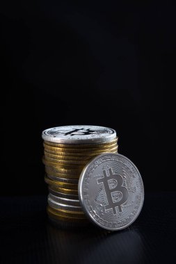 Bir gümüş bitcoin ve arka planda bir yığın bitcoin