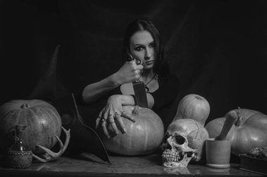 Güzel gotik kız balkabağı ve bıçakla poz veriyor.