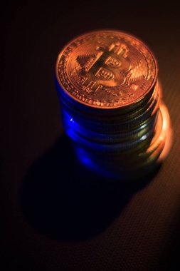 Karanlık yüzey üzerinde neon ışıklarda bitcoin yığını