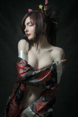 Güzel çıplak Asyalı kız karanlık arka planda poz veriyor.