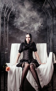 Esmer arka planda duman içinde poz veren güzel gotik kız.