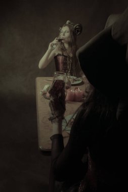 Cadı şapkalı kız ve boynuzlu kız yemek yiyor.