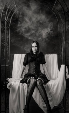 Esmer arka planda duman içinde poz veren güzel gotik kız.