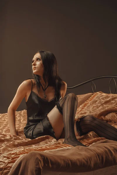 Yatakta Oturan Siyah Elbiseli Güzel Bir Kadın — Stok fotoğraf