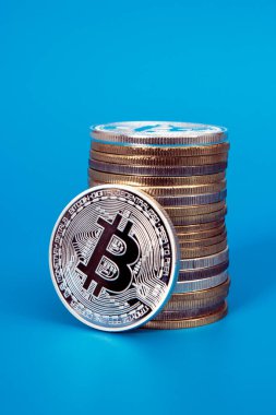Bir gümüş bitcoin ve mavi arkaplan üzerinde bitcoin yığını