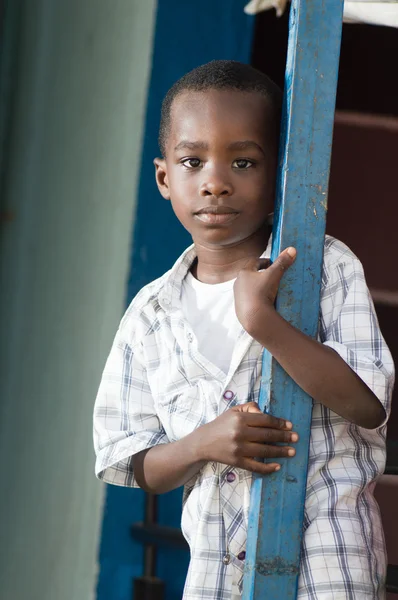 Niño africano de pie cerca de pilotes de hierro . — Foto de Stock