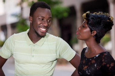 Arka planda şehir olan gülümseyen bir çift. Yakışıklı romantik bir adam ve güzel bir kadın akşam yürüyüşünün tadını çıkarıyor..