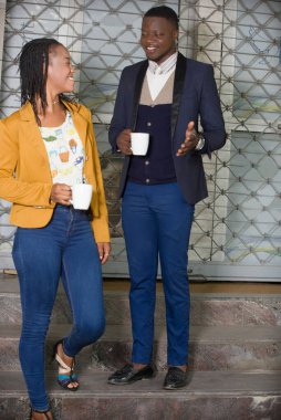 Genç iş adamları şirketlerinin önünde durmuş çay içerek gülüyorlar..