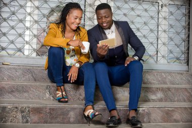 Genç iş adamları işlerinin önünde oturmuş cep telefonlarına bakıp gülümsüyorlar..