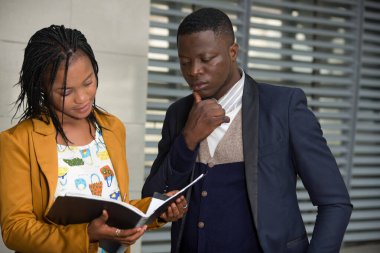 Mutlu iş adamları, resmi giyinmiş kadın ve erkek bir iş planı ya da açık hava projesini incelerken ayakta duruyorlar. konsept toplantısı ve ortaklık