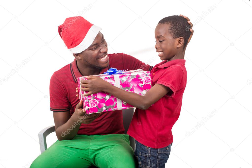 Funny smiling family, father and son with christmas hat on their head hold a present in hand.
