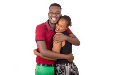 Genç bir çift birbirine dolanmış beyaz bir arka planda kameranın gülümsemesini seyrediyor..